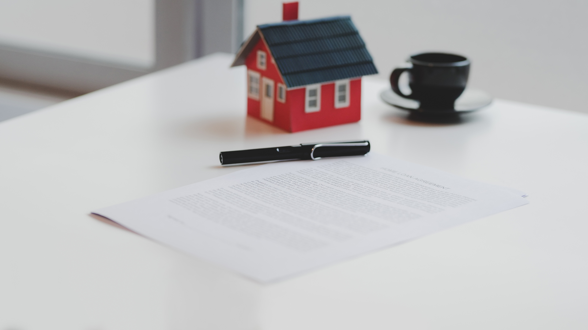 Cropped shot of home loan agreement document with small house model